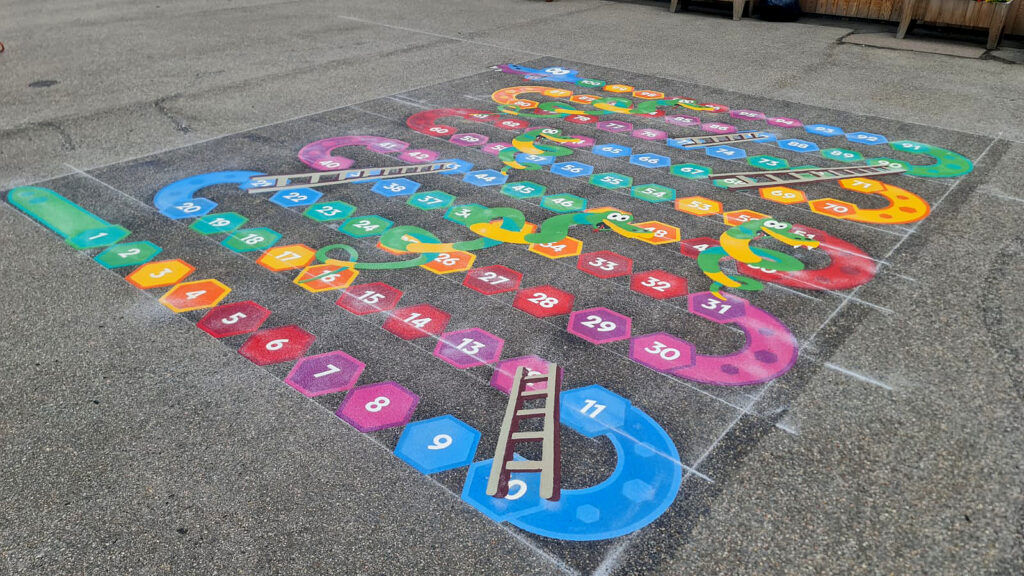 Three-dimensional snakes and ladders markings that appear to rise off the playground