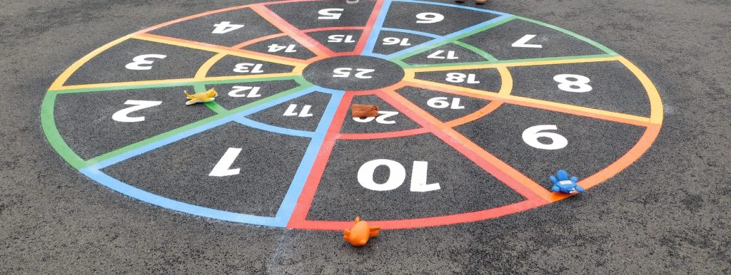 Rainbow thermoplastic number target with 1 to 20 in two rings and 25 at the centre, with soft toys tossed onto it
