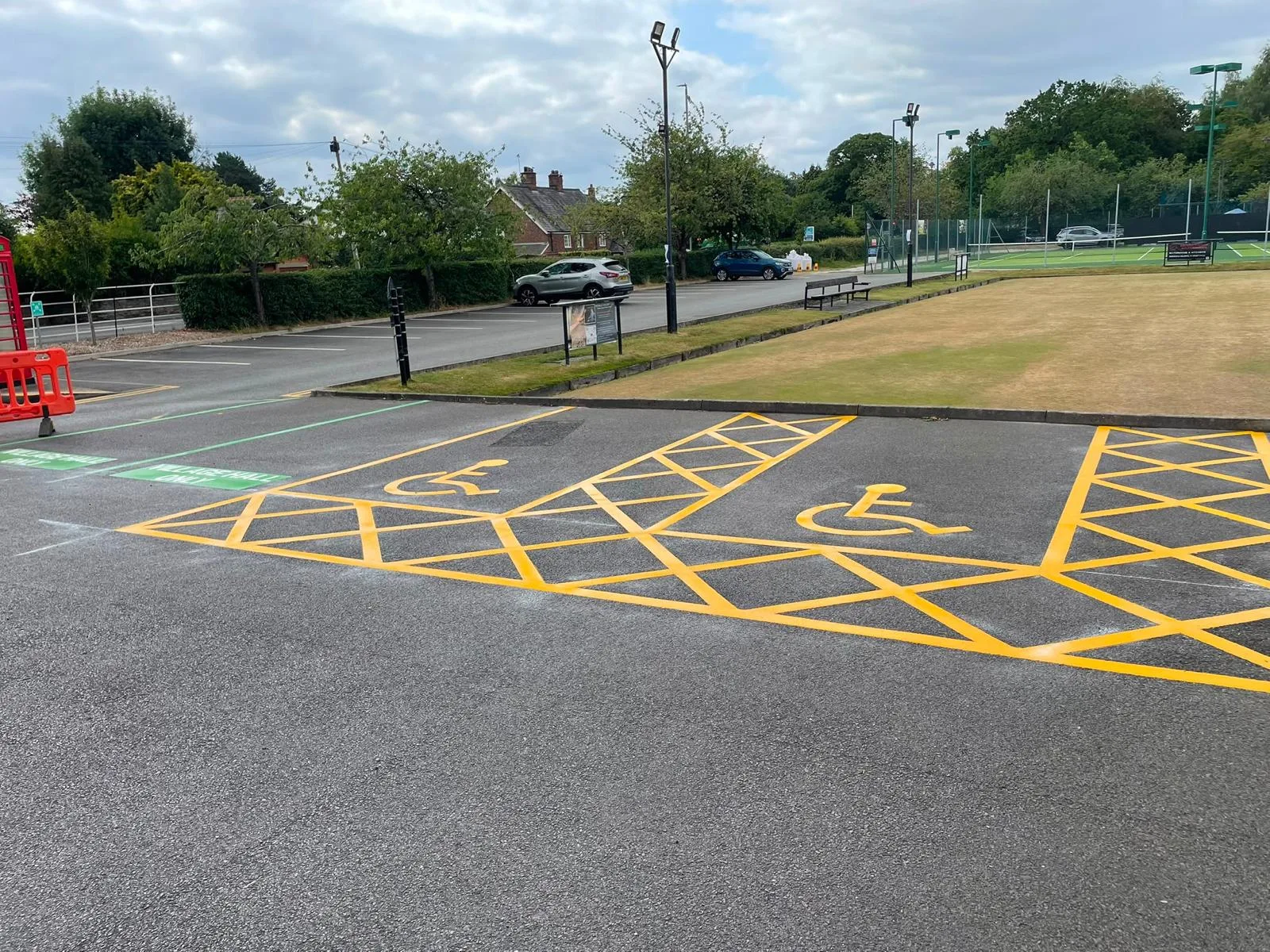 Disabled parking bays with wheelchair symbols and yellow keep-clear hatching freshly marked on a commercial car park