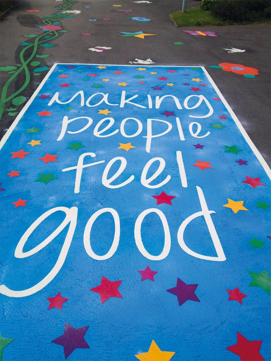 Entrance path at The Academy of Trinity C of E with a starry blue panel that reads Making people feel good, and a green vine