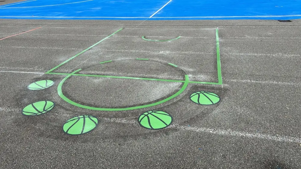 Basketball Court key marked in green with green basketball spots beside a blue sports surface