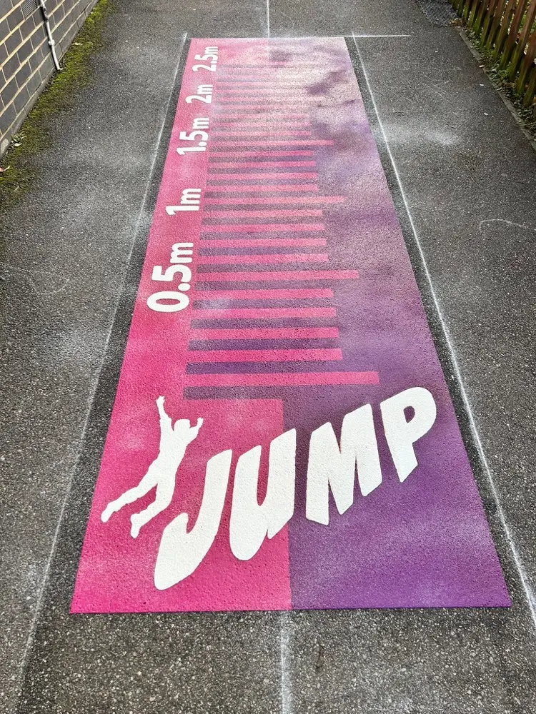 Pink and purple Long Jump run marked in metres with a leaping JUMP silhouette on a narrow tarmac strip