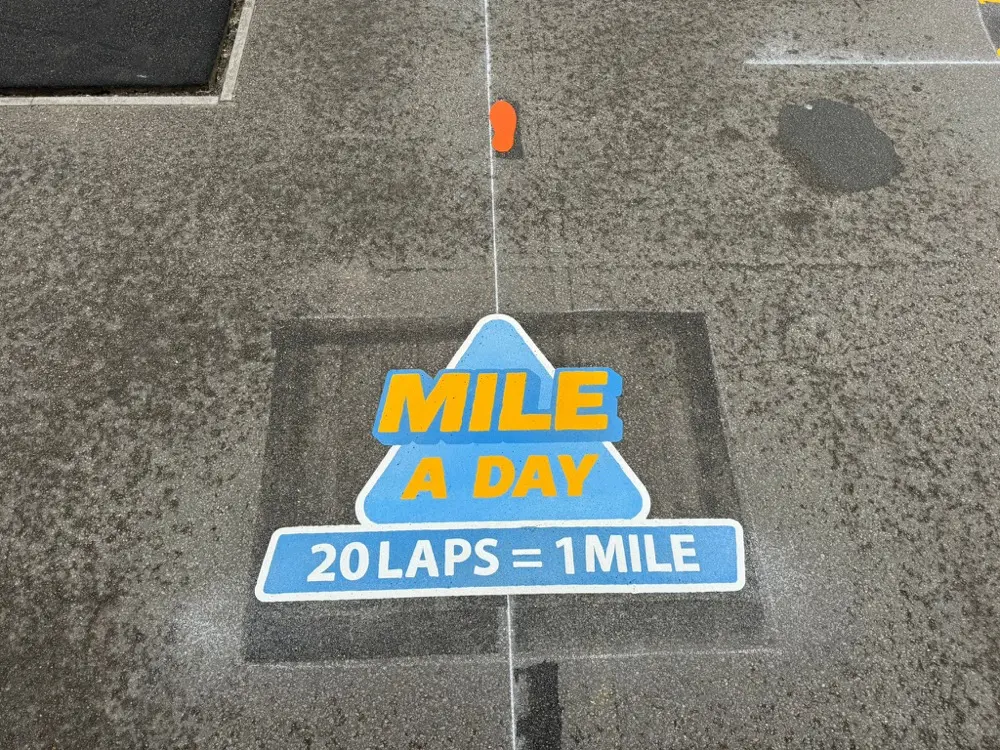 Blue Mile a Day track sign reading 20 laps equals 1 mile on dark wet tarmac