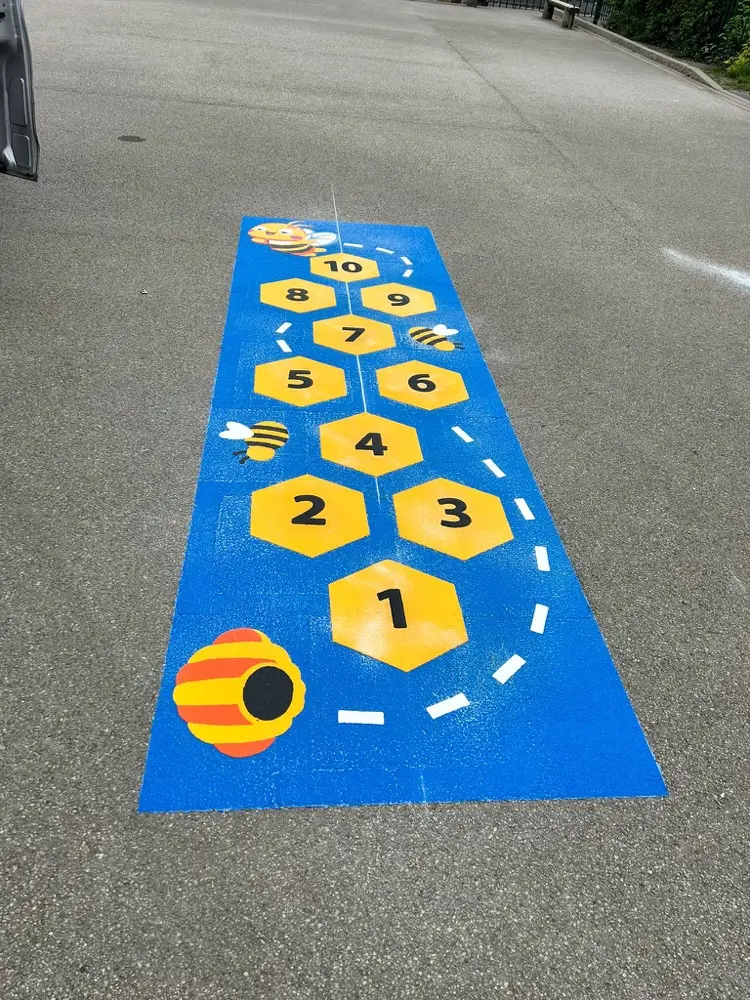 Bee Hopscotch set on a bright blue panel with yellow hexagons, a beehive and buzzing bees