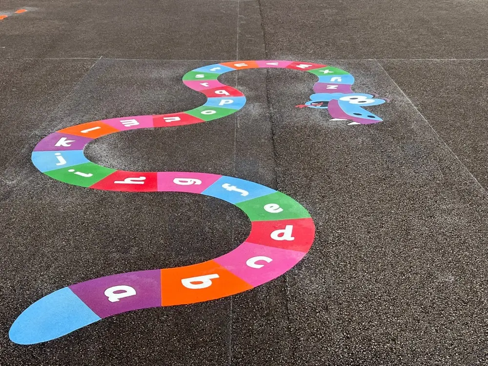 A to Z Snake curving across plain grey tarmac, lowercase letters in alternating bright blocks