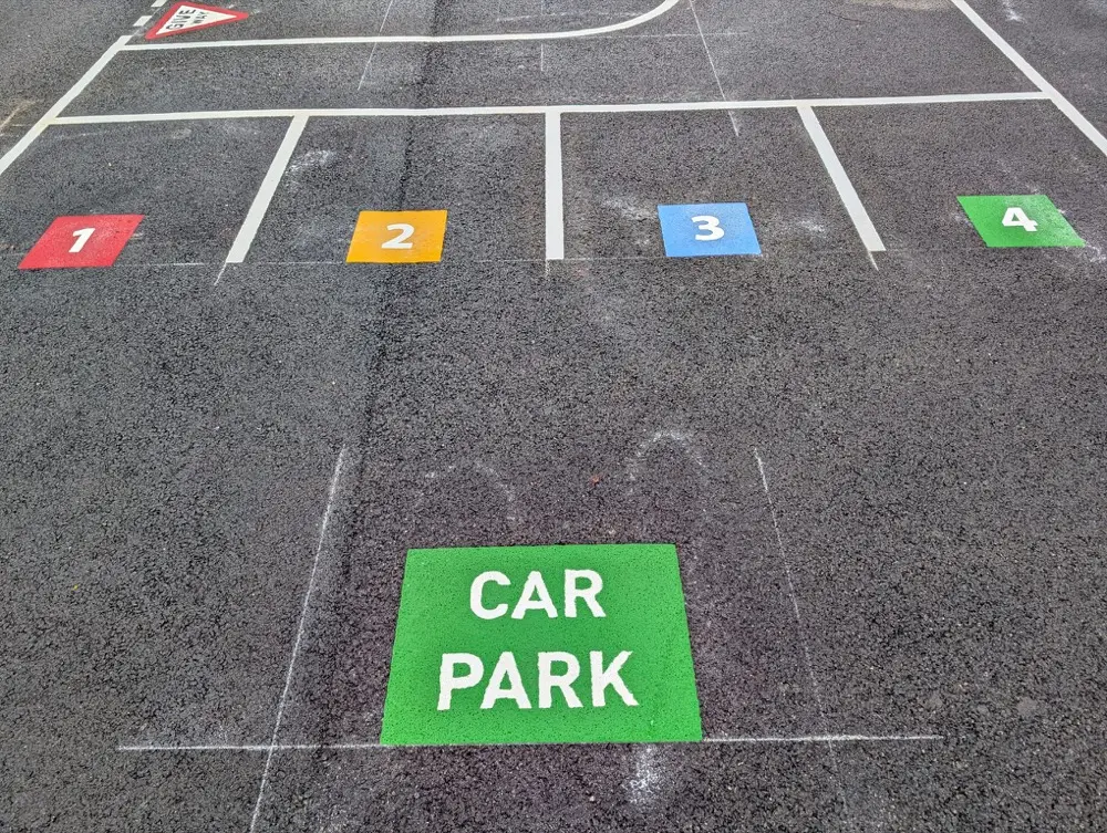 Roadway markings with coloured numbered squares and a green CAR PARK box on wet tarmac