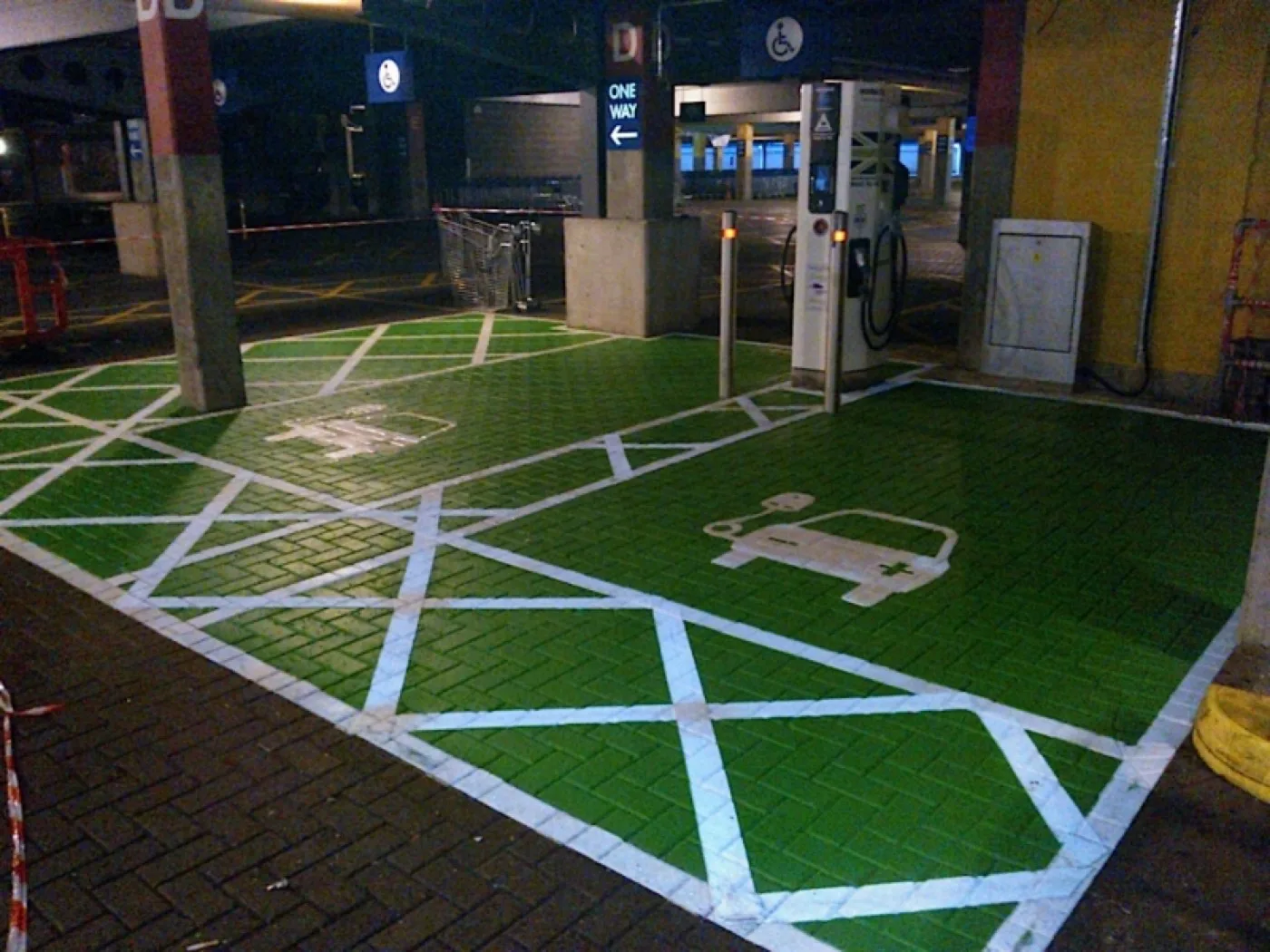 Green-painted disabled and EV charging bays outlined in white hatching inside a covered multi-storey car park