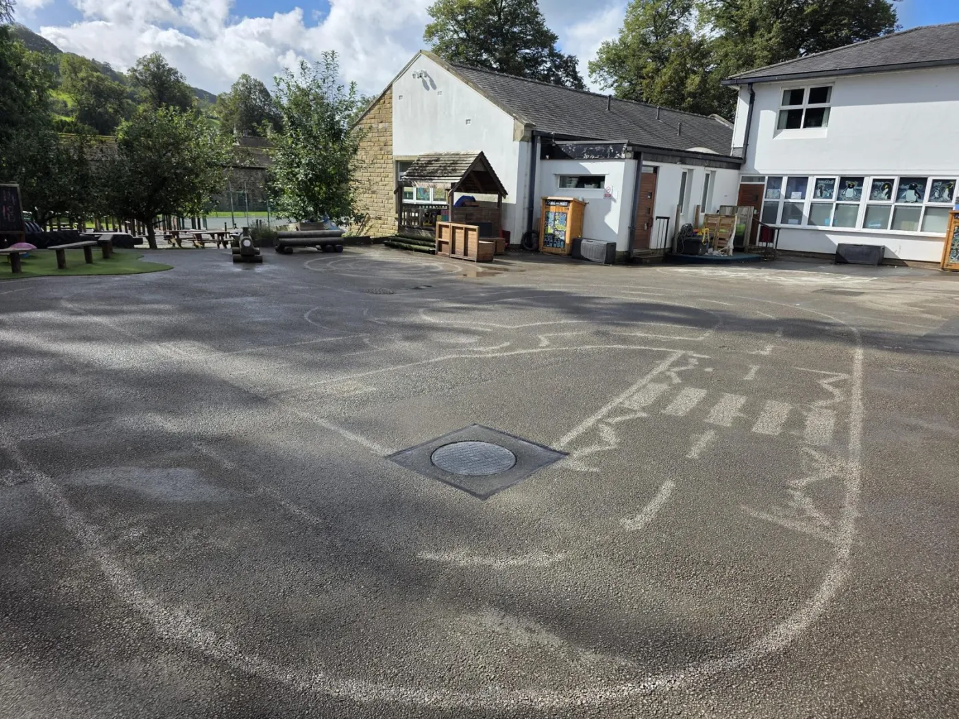 Wide playground with pale residual circle and arc outlines left after thermoplastic markings were removed