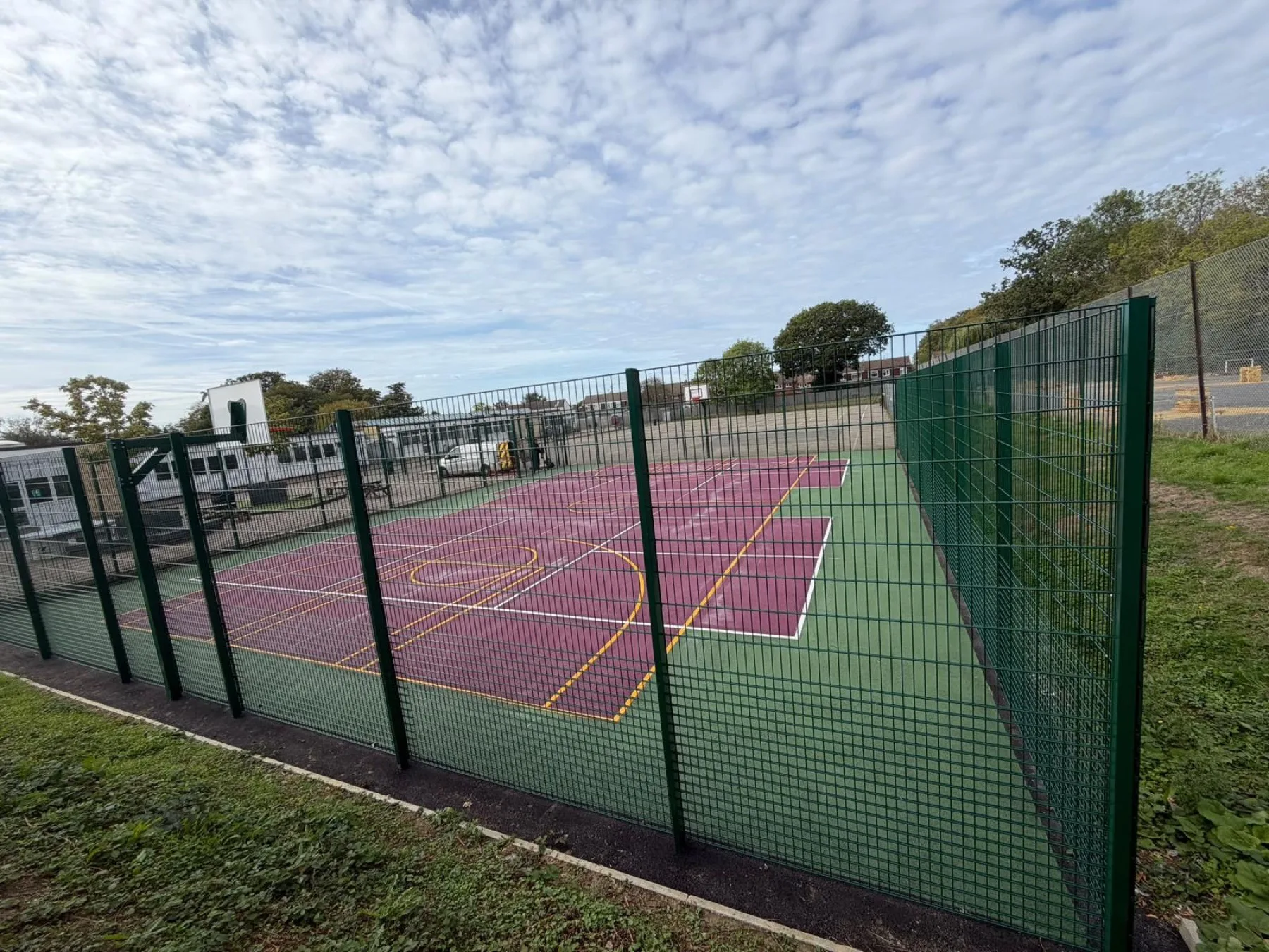 Coloured MUGA surface in purple with a green surround and mesh fencing