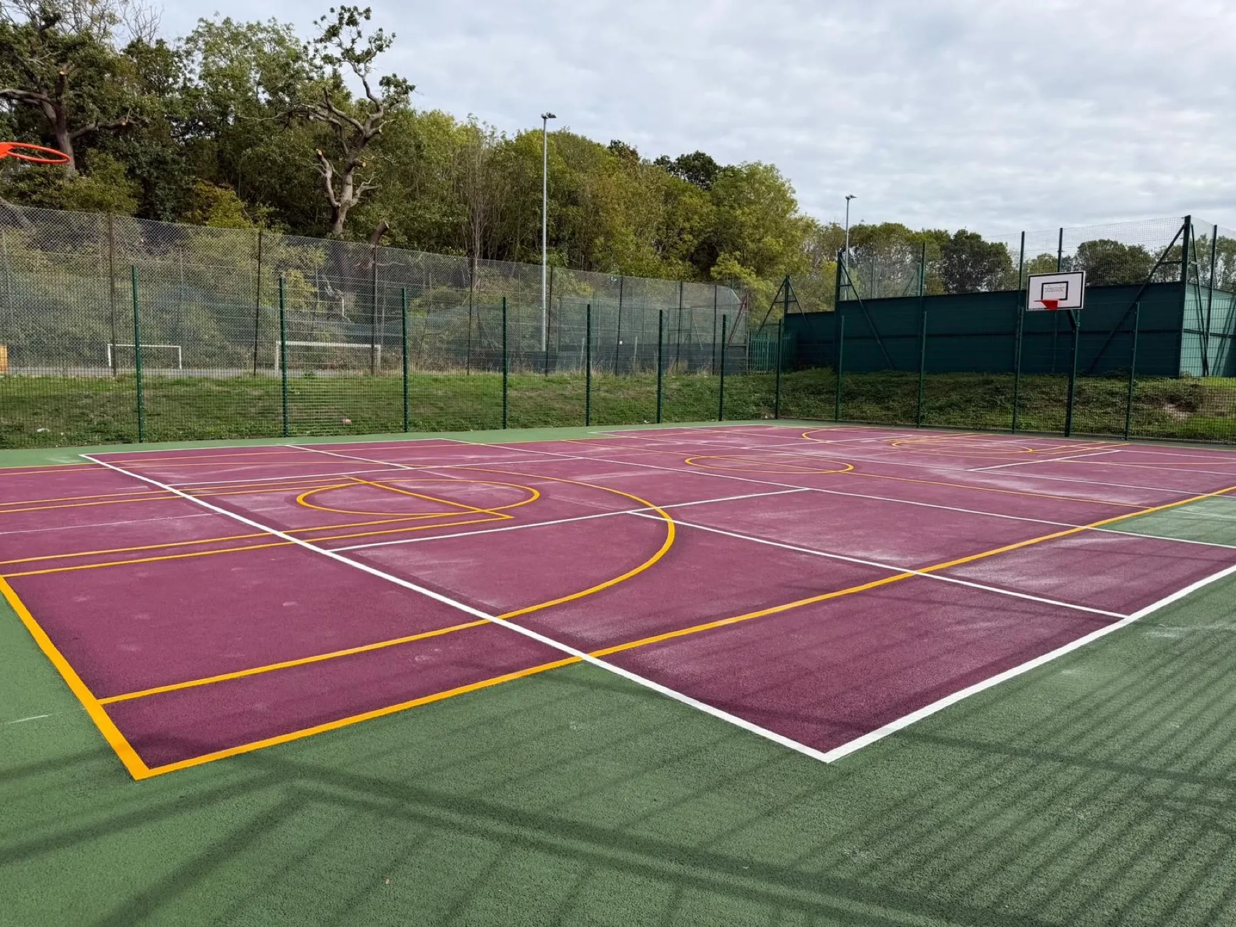 Full-colour sports court with netball and basketball lines in yellow and white