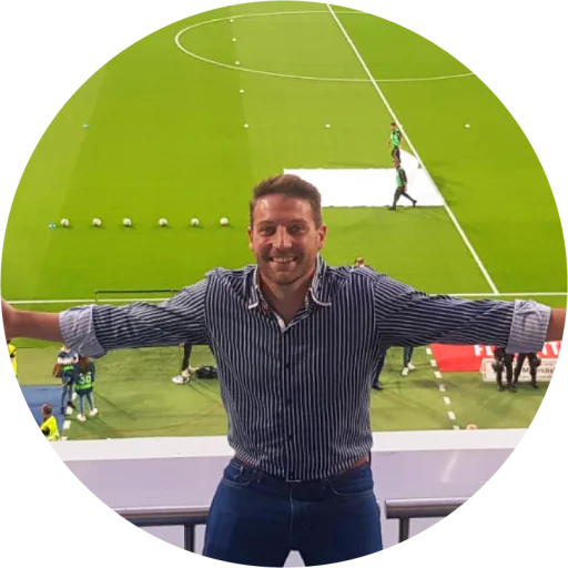 Michael Jarvie, Operations Director at Uniplay, smiling in a striped shirt with a row of footballs on the pitch below