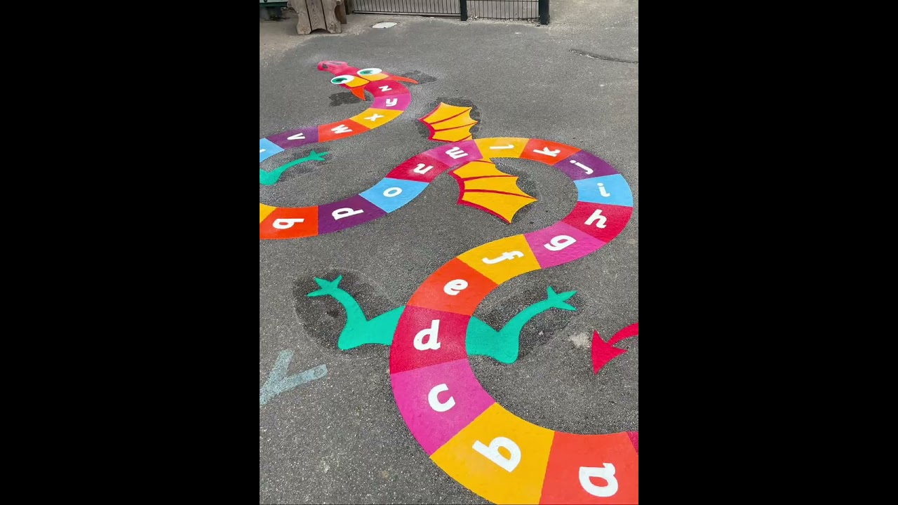 Still from a video of an alphabet dragon marking with letters a to z on its rainbow body, yellow wings and green legs
